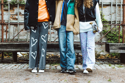 Low section of female friends standing on footpath