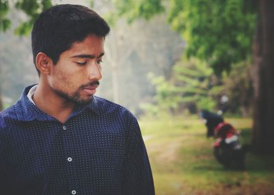 Close-up of young man looking away while standing in forest