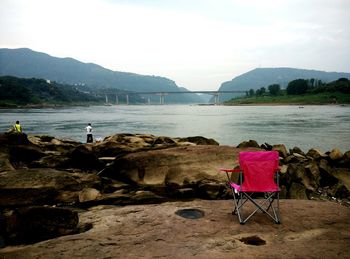 Pink chair against river and sky