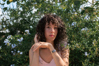 Portrait of young woman standing against trees