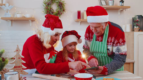 Grandparents and granddaughter preparing food at home