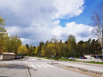 Road by trees against sky in city