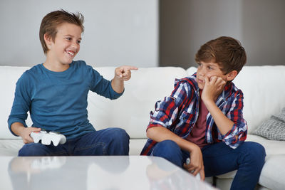 Playful boy pointing at brother while playing game