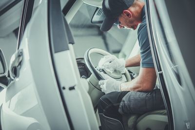 Man cleaning steering wheel of vehicle