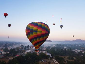 Hot air balloons flying in city against sky