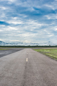 Road passing through landscape against cloudy sky