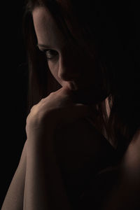 Close-up portrait of a young woman over black background