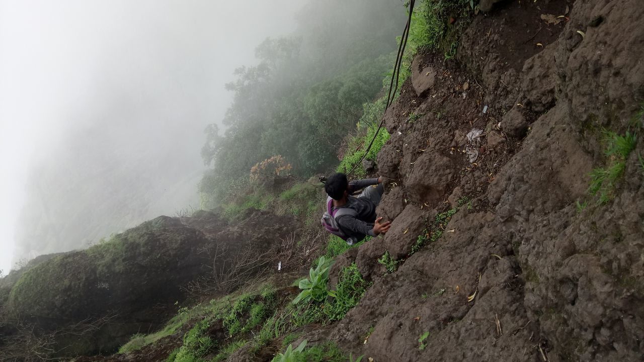 MAN STANDING ON ROCK BY MOUNTAIN