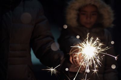 Girl with father holding illuminated sparkler at night