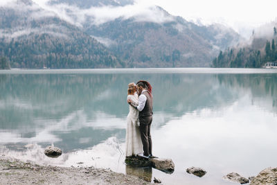 Full length of young woman standing by lake