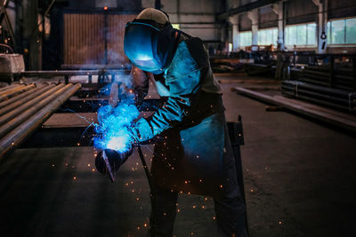 The welder works in the workshop. the moment of welding of metal structures.