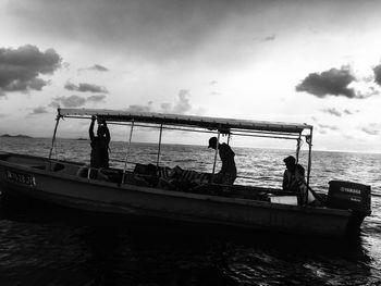 People in boat sailing on sea against sky