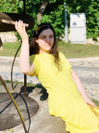 Girl in yellow sitting on the well