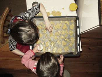 High angle view of siblings making cookies at table in house