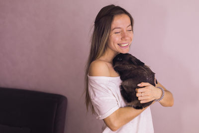 Portrait of young woman with dog at home