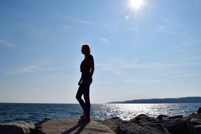 Silhouette woman standing on groyne by sea against sky