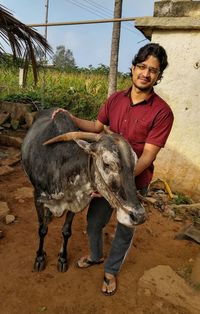 Portrait of man with cow standing on footpath