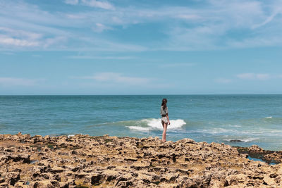 Teenage girl on the rocky shore of the northern sea.