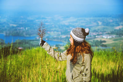 Woman standing by plants on field