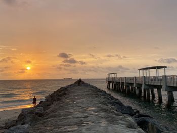 Pier over sea against sky during sunset