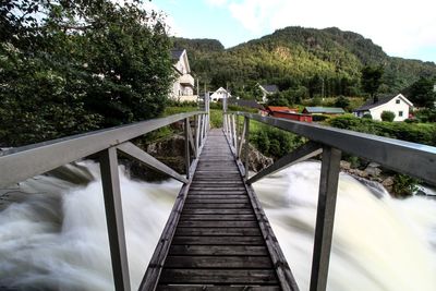 Footbridge over mountain against sky