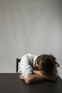 Man sitting on floor against wall at home