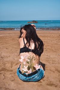 Woman wearing sunglasses at beach against sky