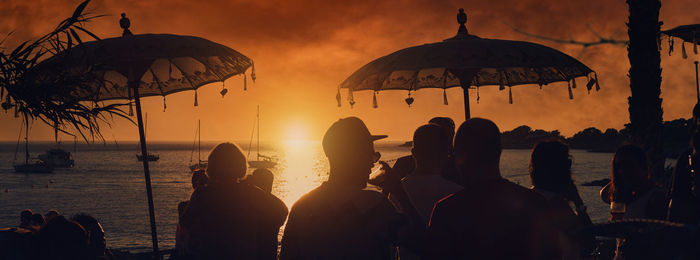 Silhouette people on beach against sky during sunset