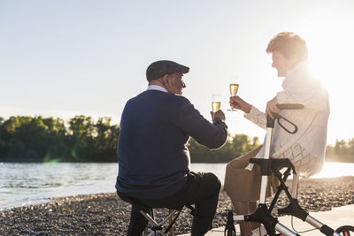 Senior couple toasting with sparkling wine at sunset