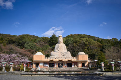 Statue by temple against sky