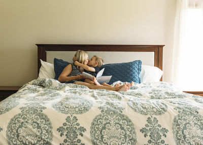 Happy mother and son while sitting on bed