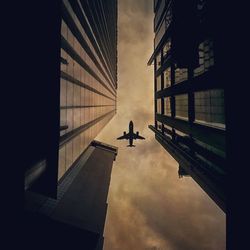 Low angle view of silhouette airplane flying against sky