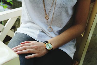 Midsection of woman sitting on chair outdoors