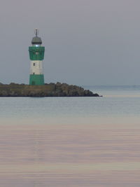 Lighthouse by sea against sky