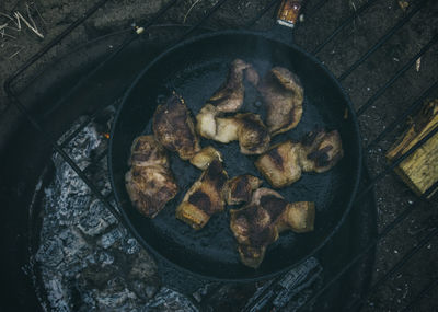 Directly above shot of fried meat in pan on wood burning stove