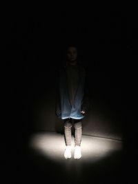 Full length of a girl standing against black background