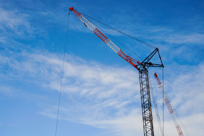 Low angle view of cranes at construction site against sky