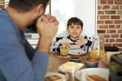 Son talking while eating food at home