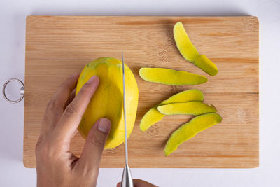 Close-up of hand holding fruits on cutting board