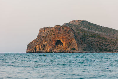 Rock formation in sea against clear sky