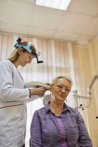 Ent physician examining ear of a senior woman