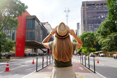 Rear view of young beautiful tourist woman on the paulista avenue, sao paulo, brazil.