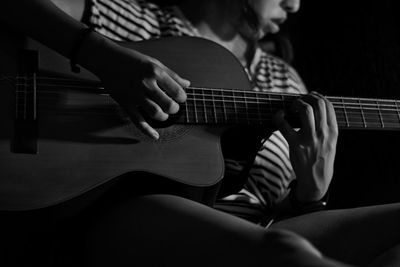 Midsection of woman playing guitar