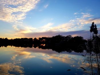 Silhouette trees by lake against sky during sunset