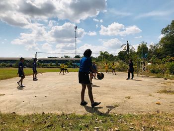 Girls playing volleyball against sky on sunny day