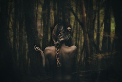 Rear view of sensual woman standing against forest