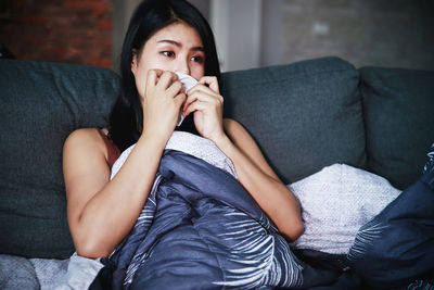Portrait of woman sitting on sofa at home