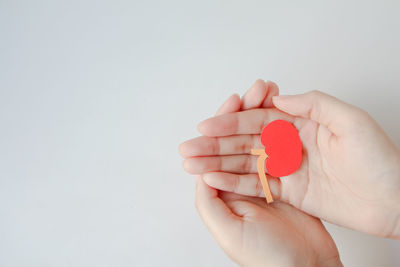 Cropped hand holding red heart shape against white background