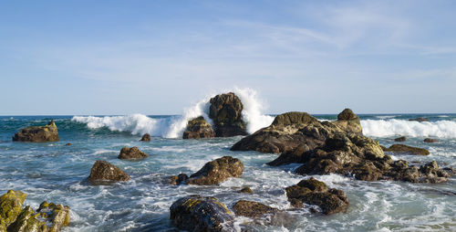 Scenic view of rocks in sea against sky