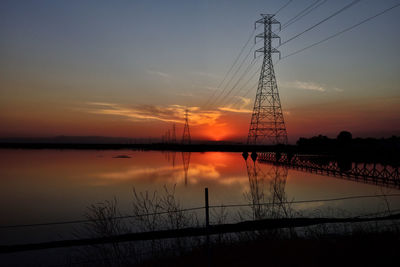 Silhouette electricity pylon against sky during sunset